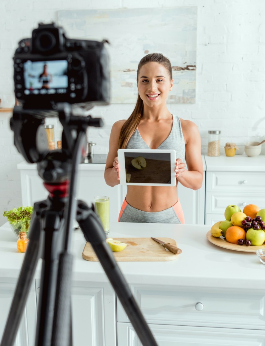 selective focus of happy video blogger holding digital tablet with blank screen