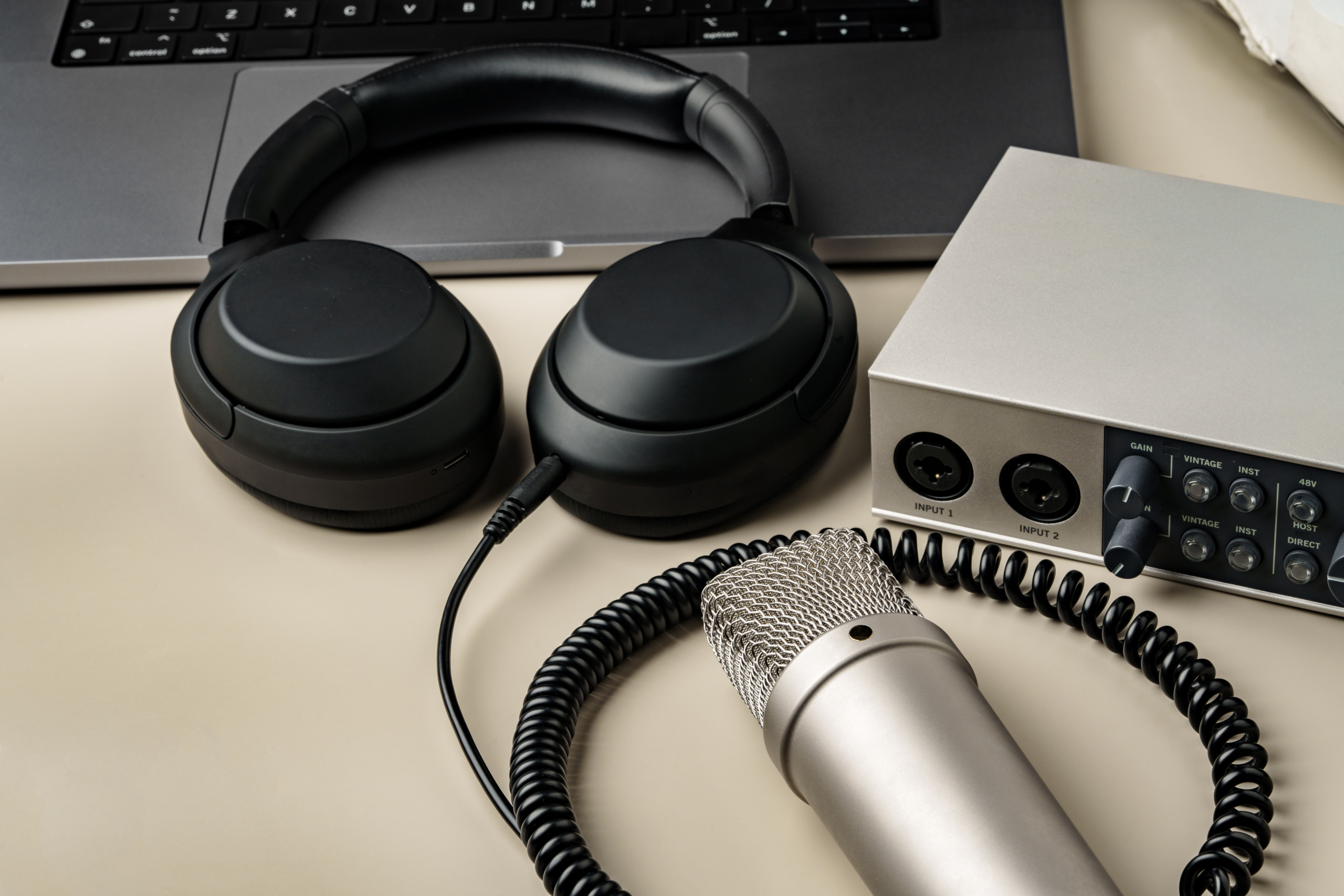 A pair of headphones and a professional microphone on a table.